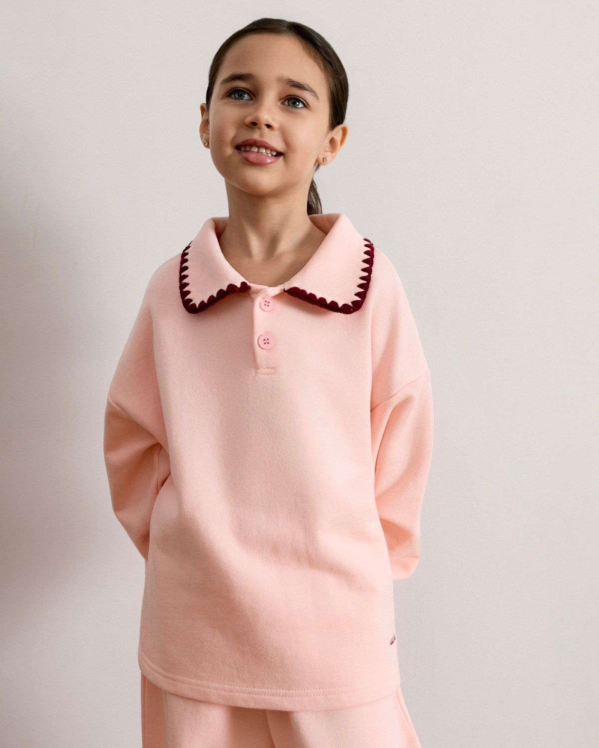 Close-up of the Avaacha Mimi Tracksuit top with dark raspberry crochet collar