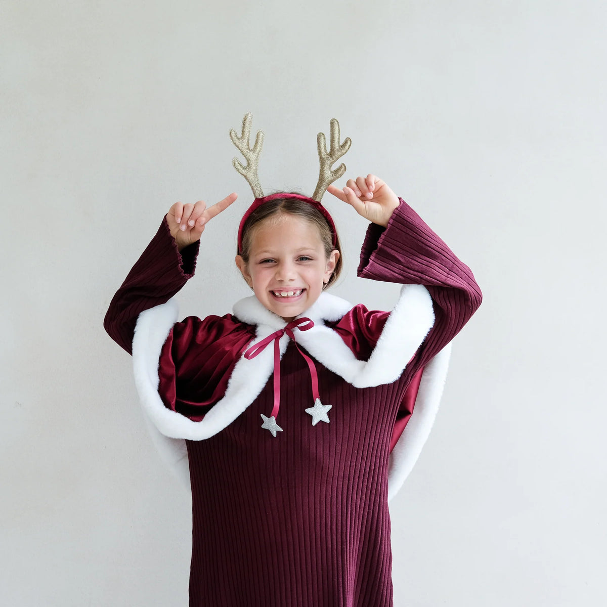Girl in a cape wearing the Rudolph antlers headband