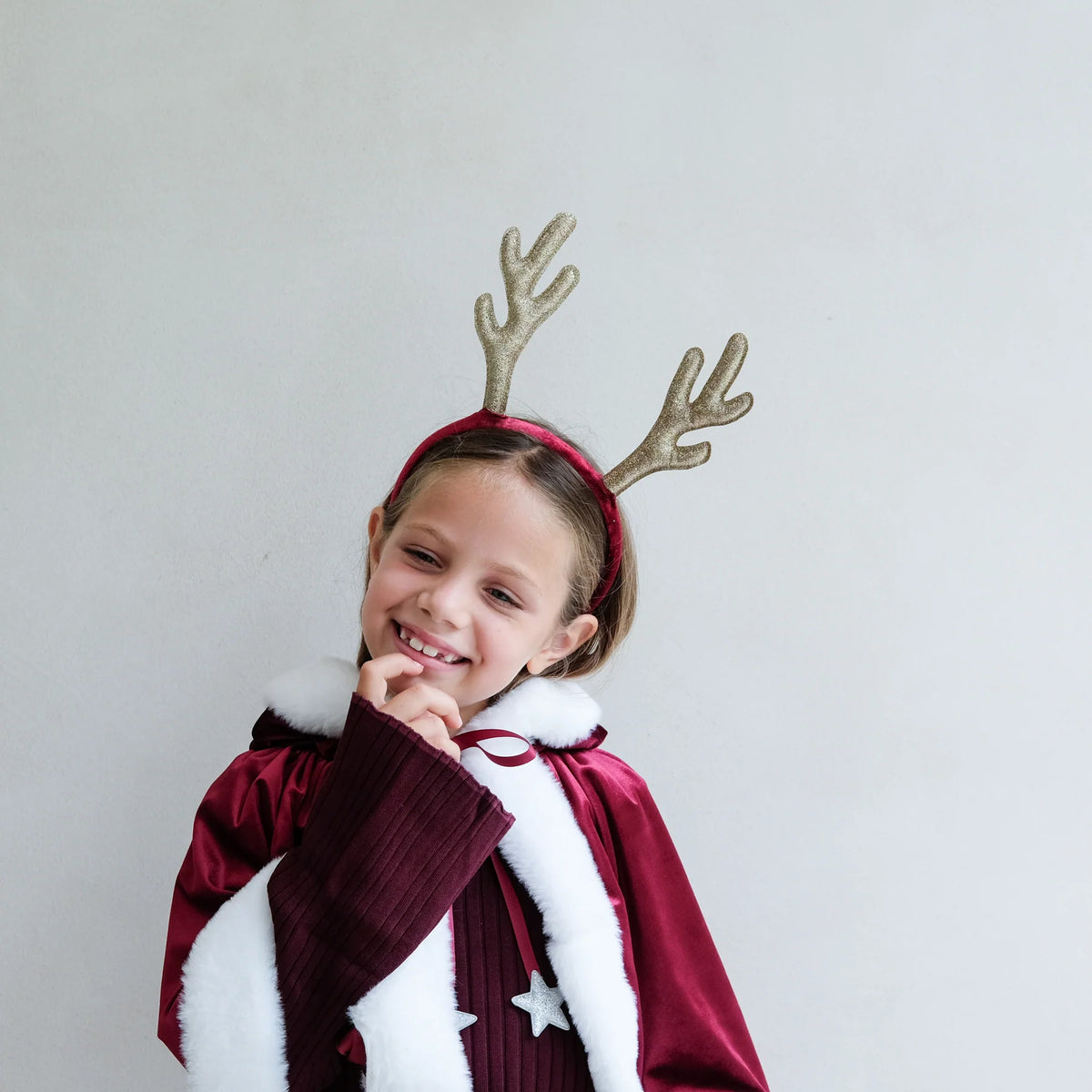 Child in a red cape and Mimi & Lulu reindeer antlers