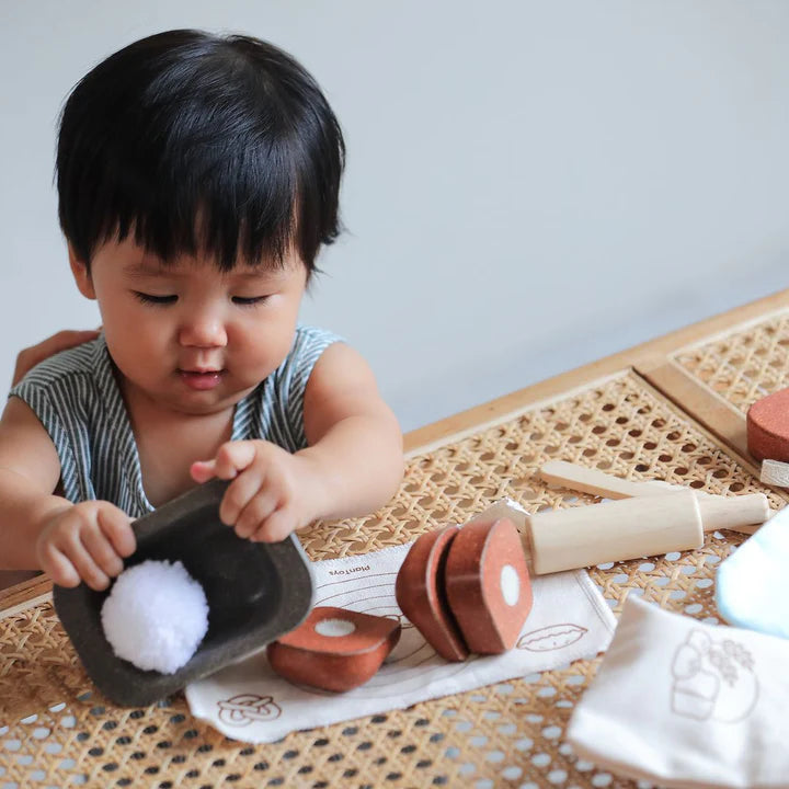 Toddler playing with the PlanToys wooden bread loaf set