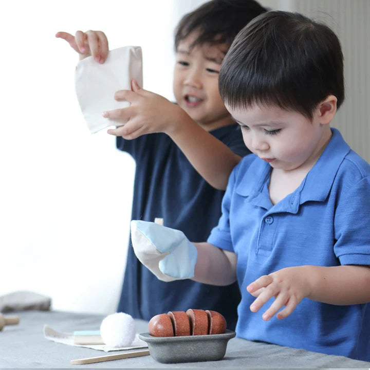 Two boys baking with the PlanToys bread loaf set