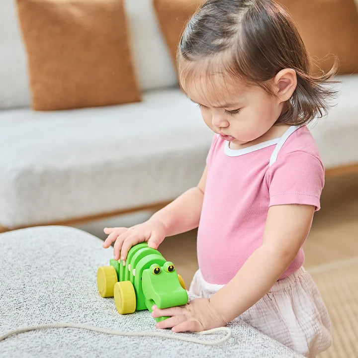 Toddler playing with the PlanToys Dancing Alligator on a sofa