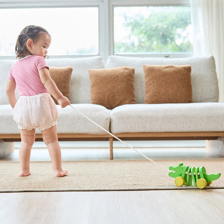 Girl pulling the PlanToys Dancing Alligator across a room