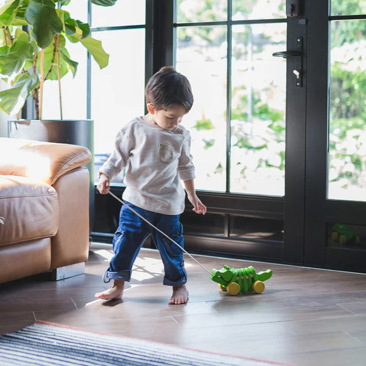 Child pulling the Dancing Alligator through a living room