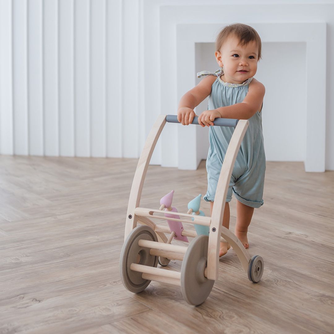 Baby standing and pushing the PlanToys Woodpecker Walker on a wooden floor