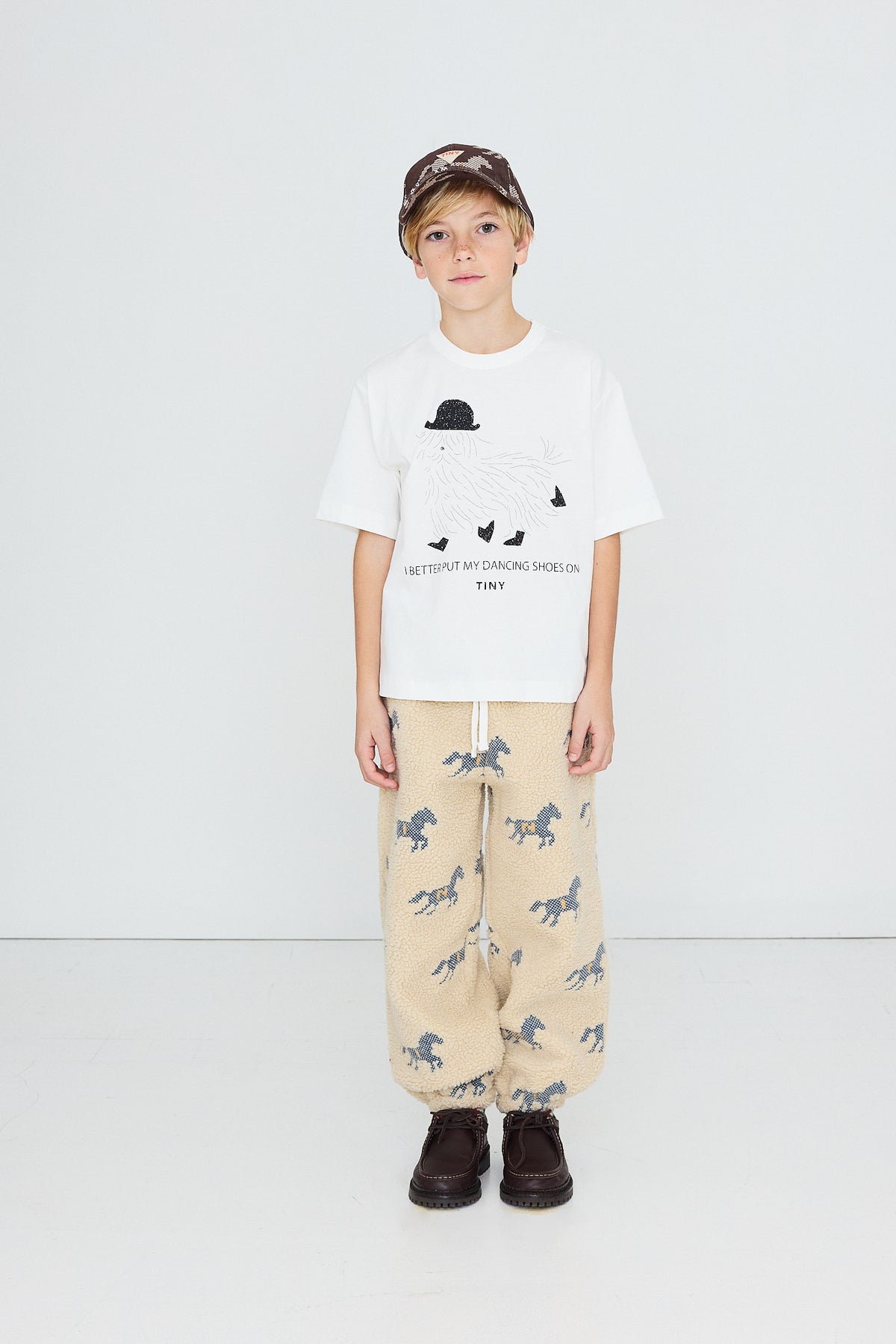 Child in a cap wearing the Tinycottons Dancing Shoes tee