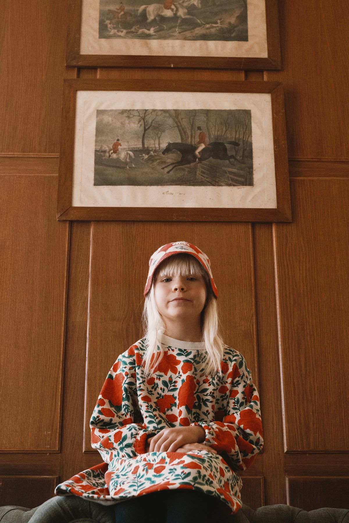 Child sitting in a wood-panelled room wearing the Tinycottons Roses dress