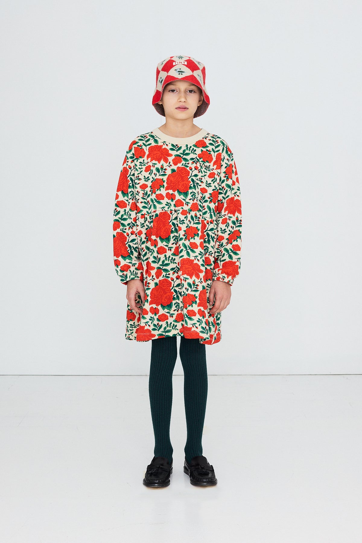 Child in a matching hat wearing the Tinycottons Roses dress