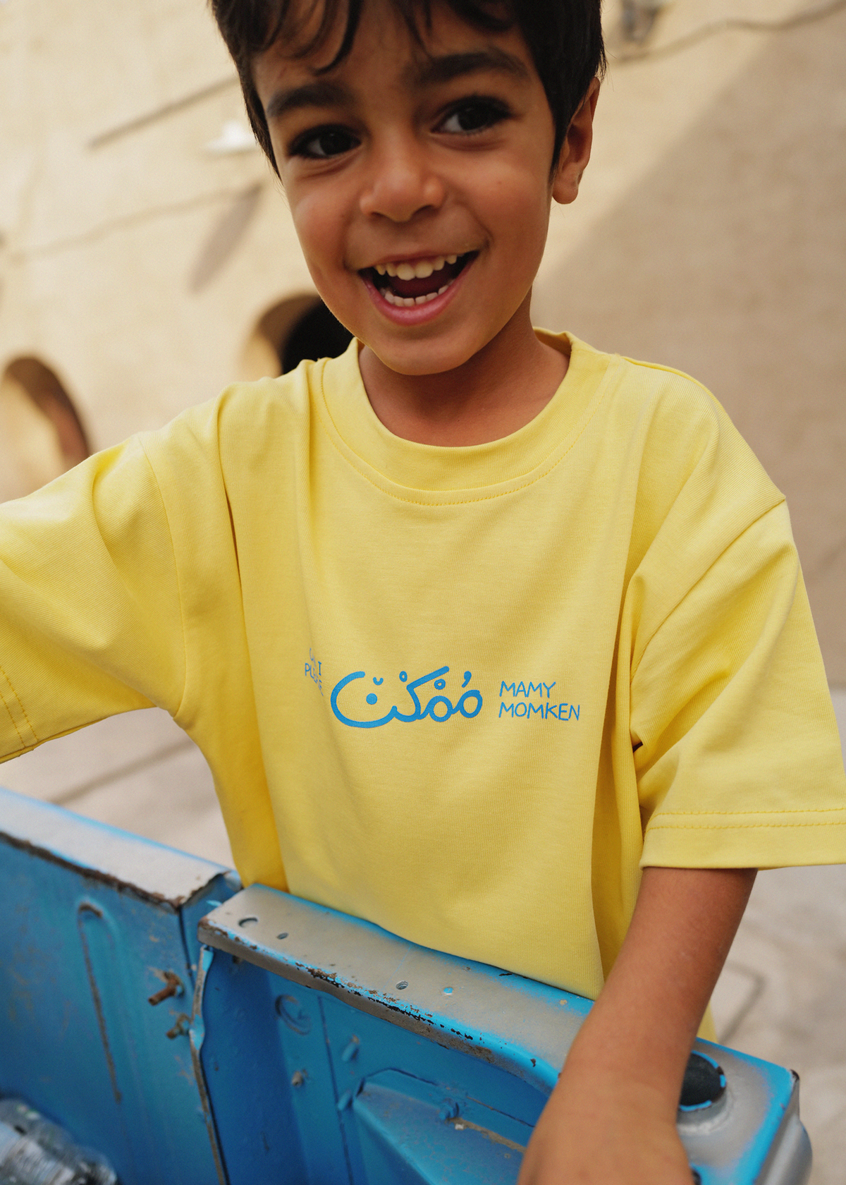 Smiling boy wearing the yellow Oupah Please Tee