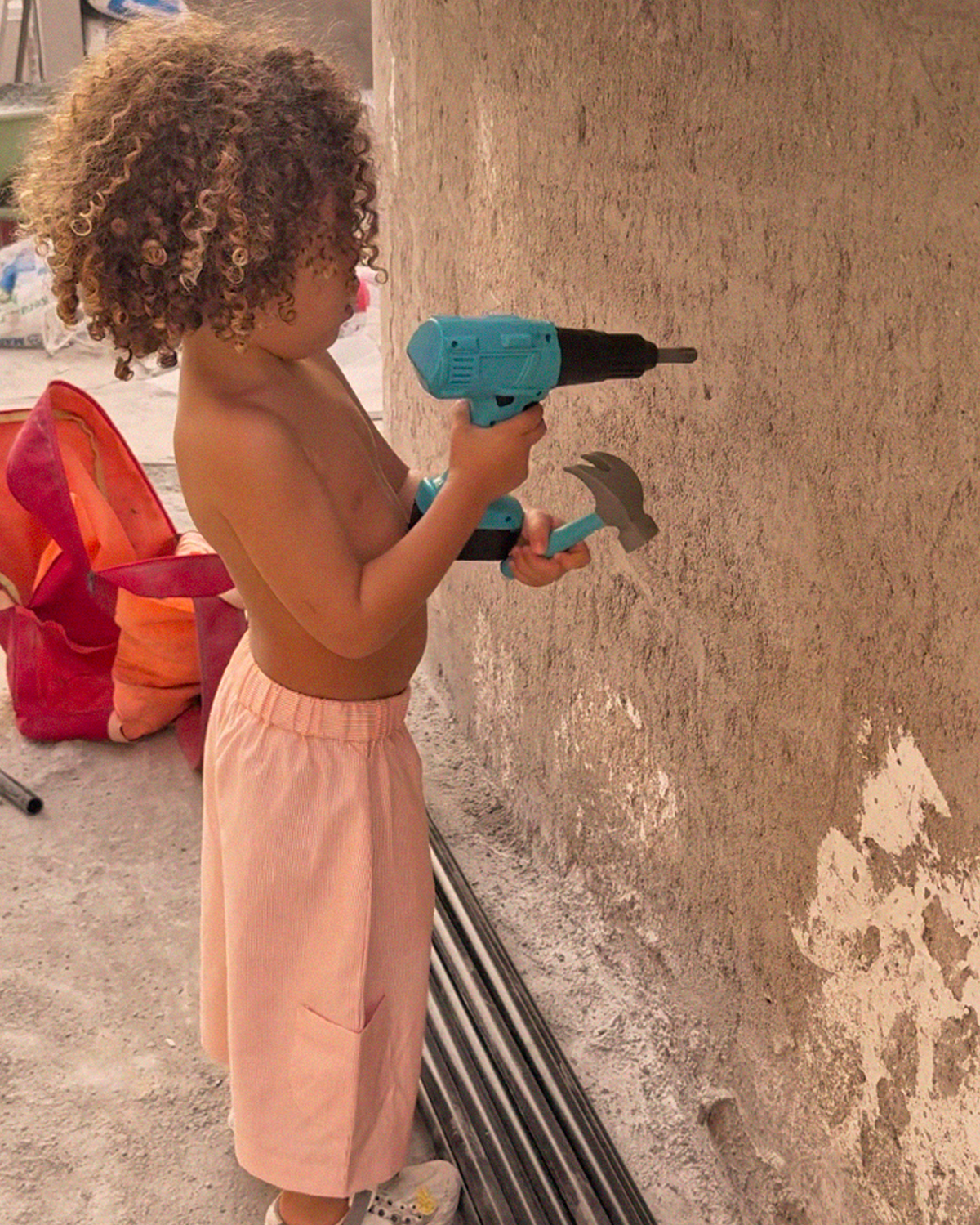 Little girl playing with a toy drill, wearing the coral stripe Oupah Explorer Capris