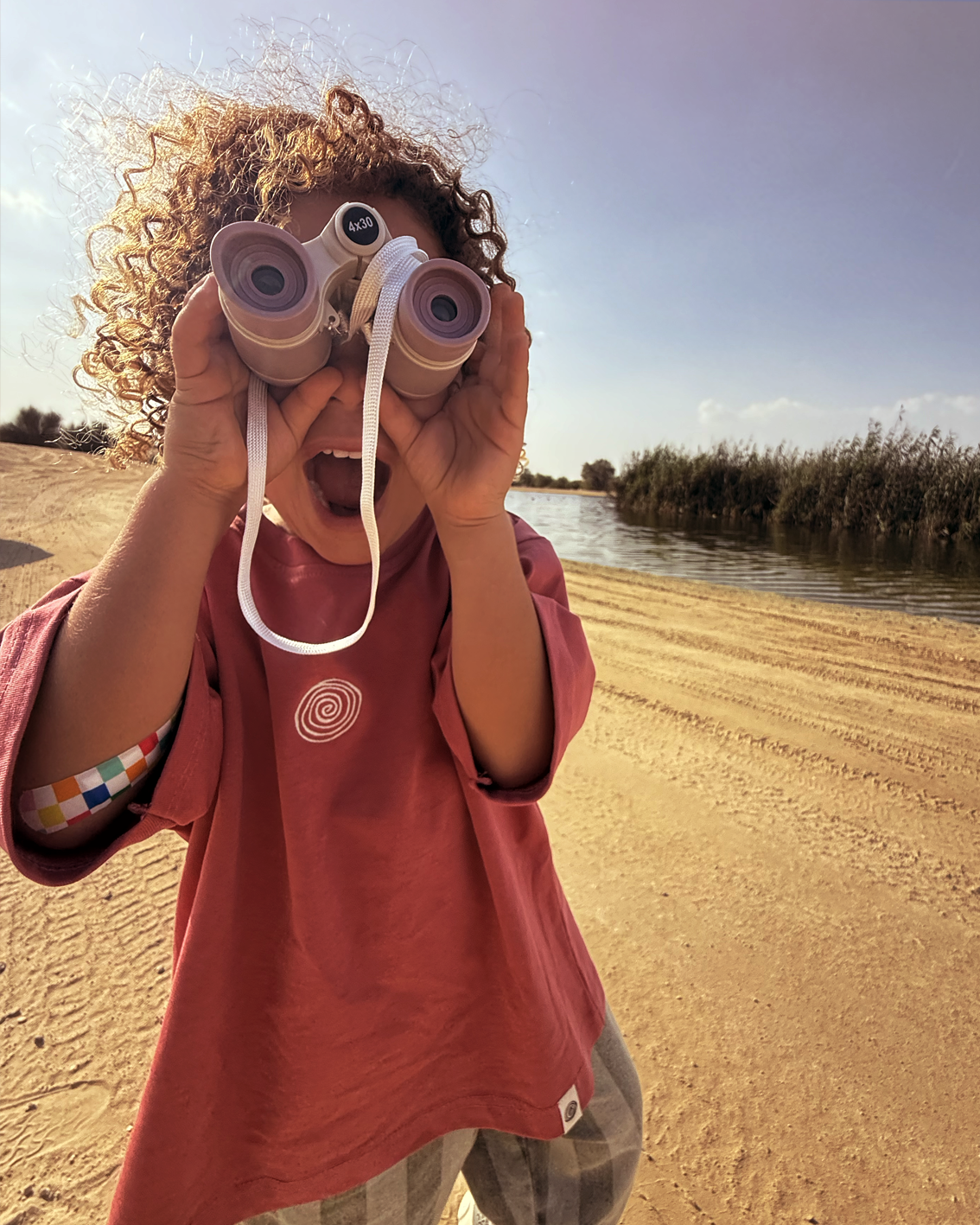 Child in the Oupah Mama Tee looking through binoculars