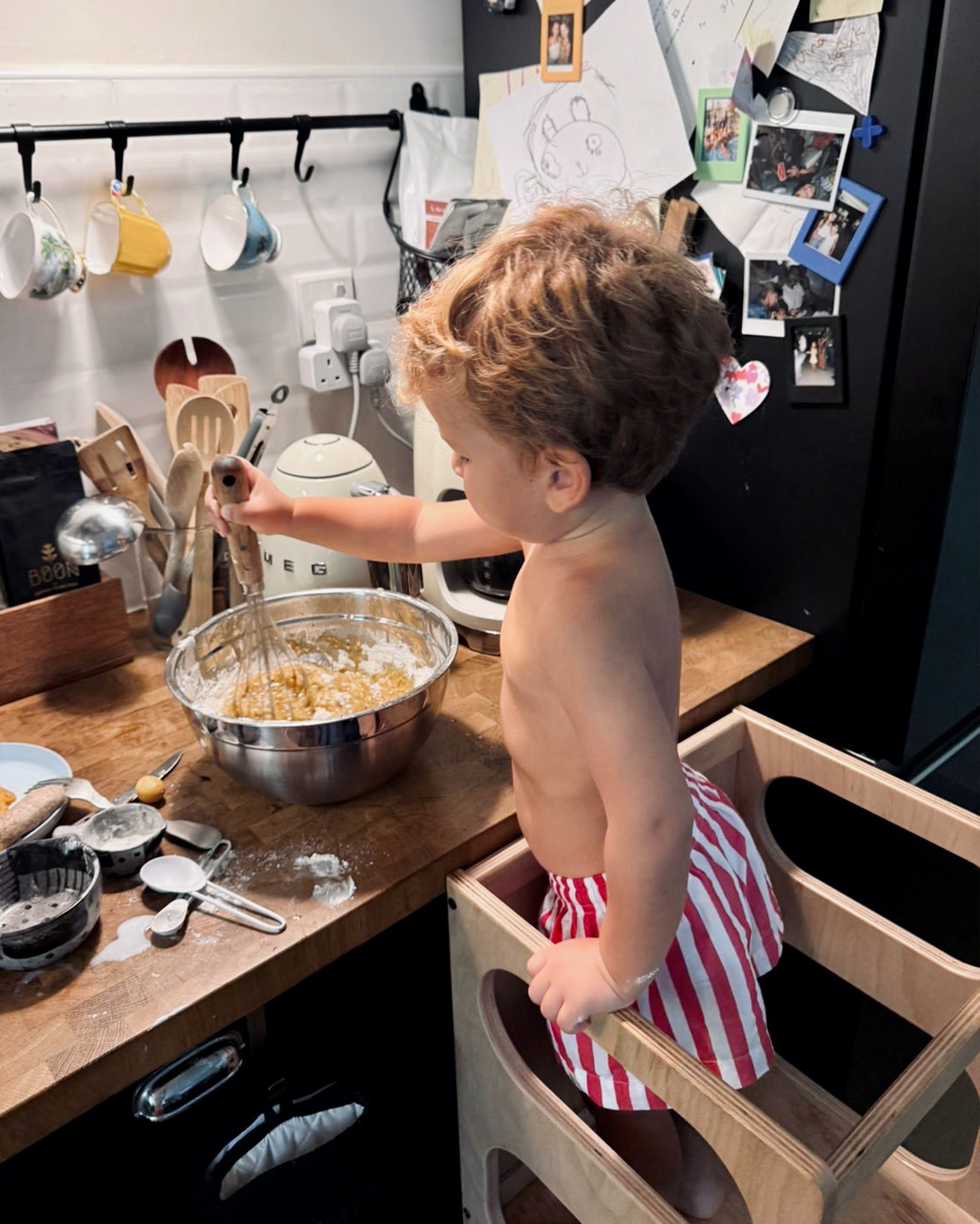 Child playing in a kitchen wearing the red and white striped Oupah Ringmaster Shorts
